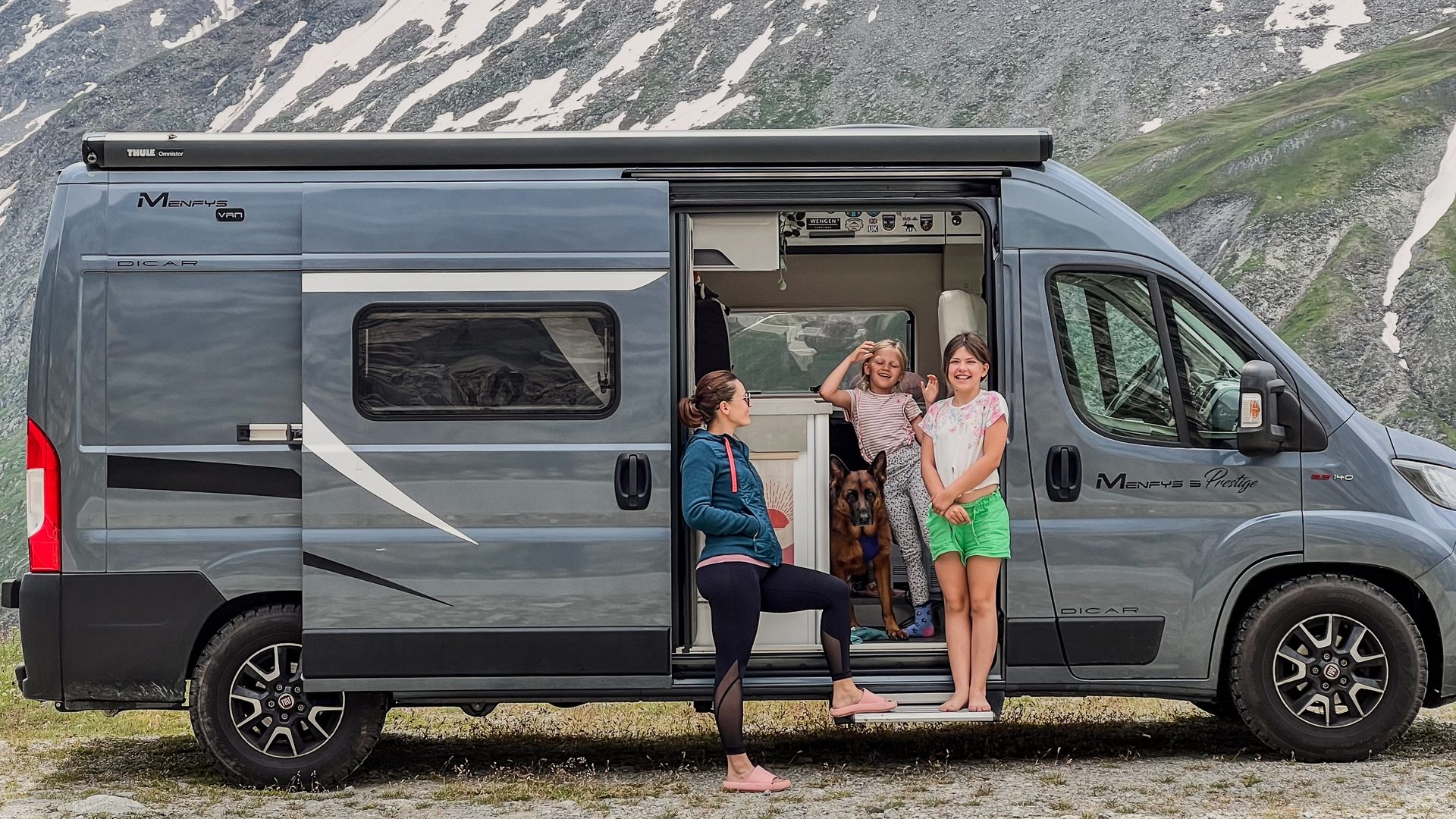 Gezin bij de opengeschoven deur van camper Freddy in de Alpen