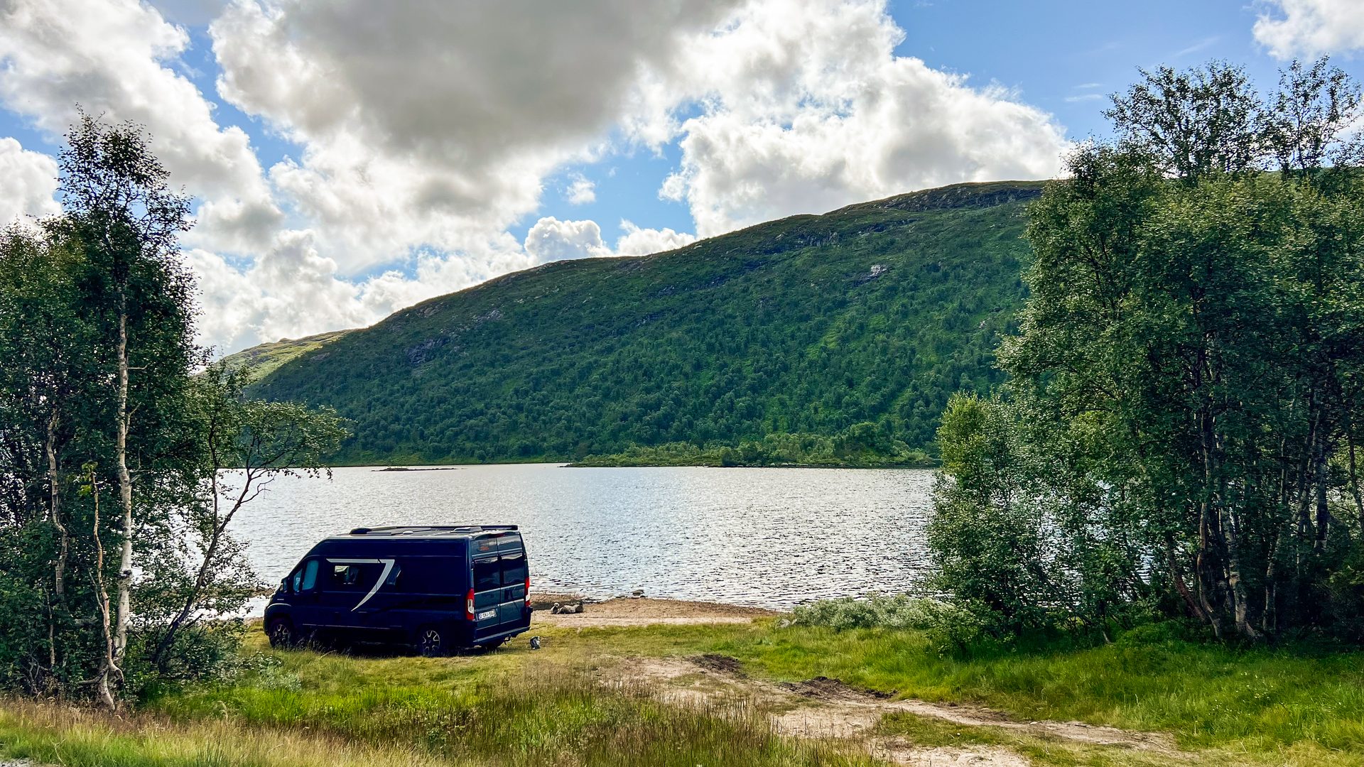 Camper Freddy geparkeerd aan een bergmeer tussen de bossen