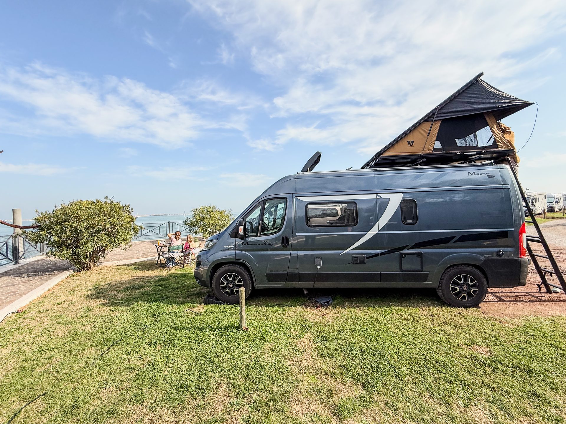 Camper Freddy met daktent open op een zonnige camping